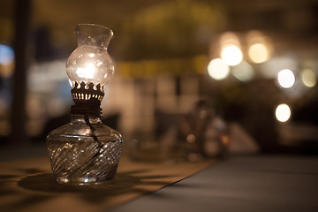 Image showing Antique oil lamp with dim light on table in cafe