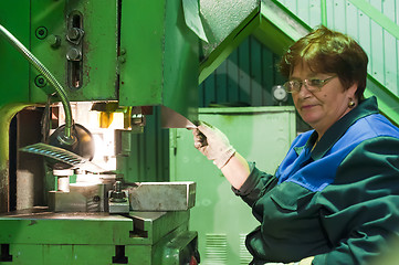 Image showing Senior female worker operates metalworking machine