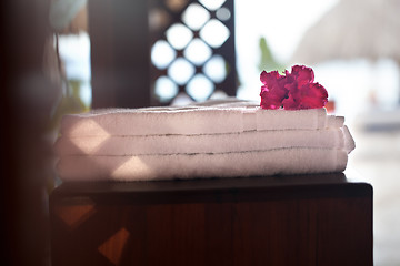 Image showing Pile of three white clean towels with flower on top