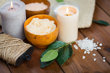 Image showing close up of natural body scrub and candles on wood