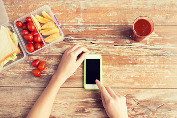 Image showing close up of hands with smartphone food on table