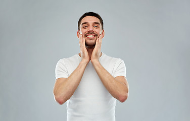 Image showing happy young man applying aftershave to face