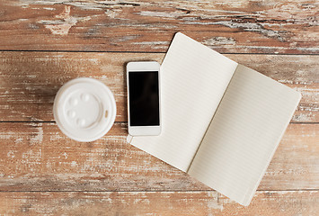 Image showing close up of notebook, coffee cup and smartphone