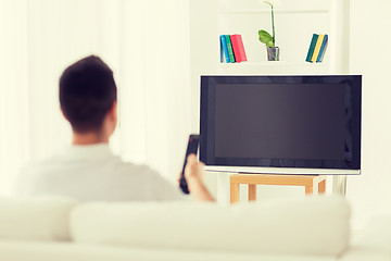 Image showing man watching tv and changing channels at home