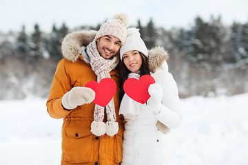 Image showing happy couple with red hearts over winter landscape