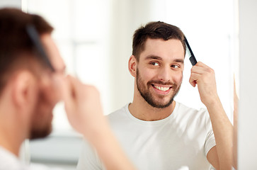 Image showing happy man brushing hair  with comb at bathroom