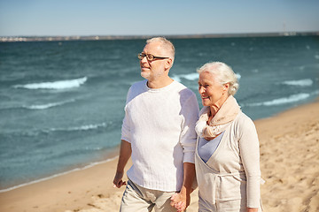 Image showing happy senior couple walking along summer beach