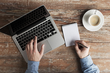 Image showing close up of male hands with laptop and notebook