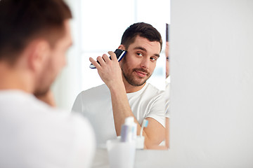 Image showing man shaving beard with trimmer at bathroom