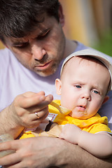 Image showing Father trying to feed infant