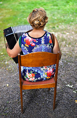 Image showing Unidentified woman from behind playing the accordion