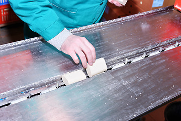 Image showing Working hand puts a bar of soap on the conveyor