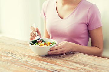 Image showing close up of young woman eating salad at home