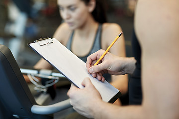 Image showing close up of trainer hands with clipboard in gym