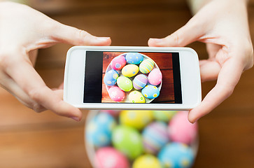 Image showing close up of hands with easter eggs and smartphone