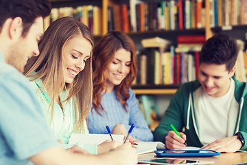 Image showing happy students writing to notebooks in library