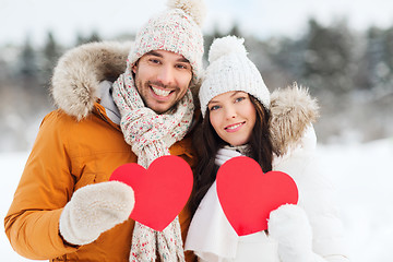 Image showing happy couple with red hearts over winter landscape