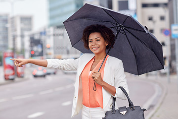 Image showing happy african woman with umbrella catching taxi