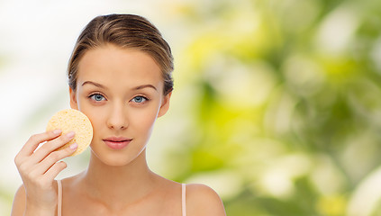 Image showing young woman cleaning face with exfoliating sponge