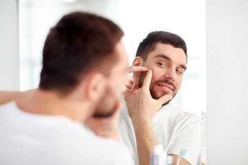 Image showing man squeezing pimple at bathroom mirror