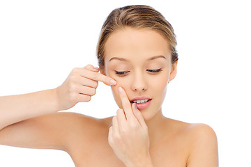 Image showing young woman squeezing pimple on her face