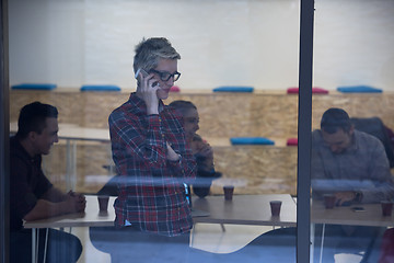 Image showing business woman at office speaking by phone  team on meeting in b