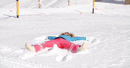 Image showing Young woman making a angel in white snow