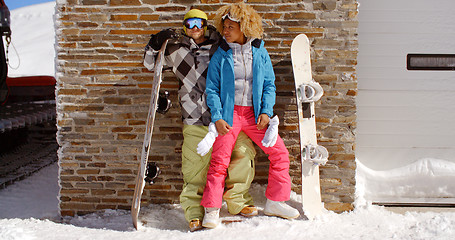 Image showing Close couple posing with snowboards against garage