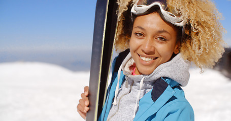 Image showing Thoughtful young woman standing holding her skis