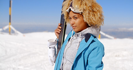 Image showing Thoughtful young woman standing holding her skis