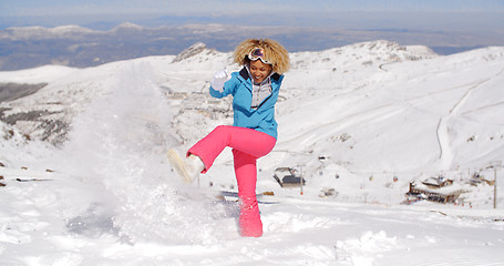 Image showing Cute woman in skiing clothes kicking snow