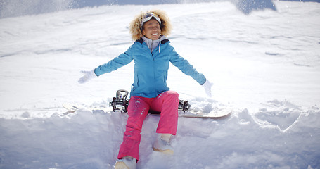 Image showing Beautiful young snowboarder sitting on snow