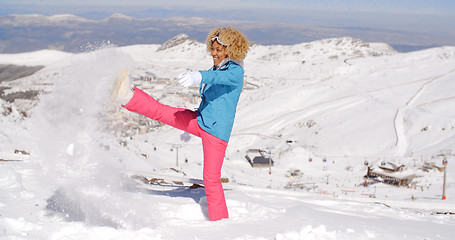 Image showing Cute woman in skiing clothes kicking snow