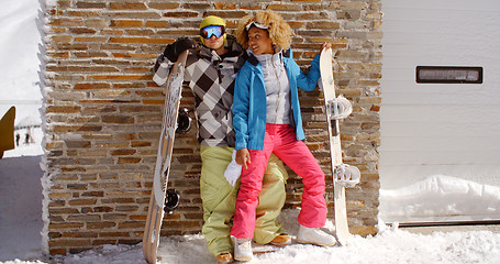 Image showing Close couple posing with snowboards against garage
