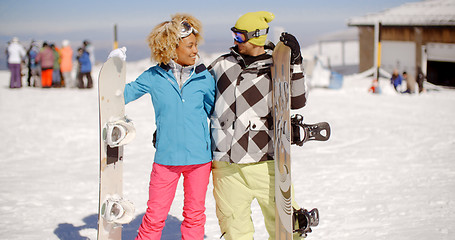 Image showing Loving young couple with their snowboards