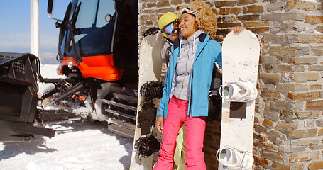 Image showing Close couple posing with snowboards against garage