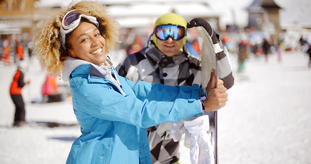 Image showing Man flirting with woman holding snowboard