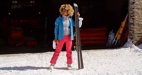 Image showing Confident young woman in snowsuit with skis