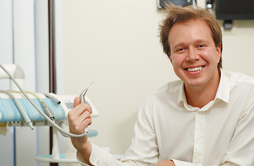 Image showing Laughing man with tousled hair holding dental tool