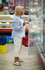 Image showing Woman choosing products in open fridge with dairy