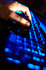 Image showing Man\'s hand typing on a blue keyboard.