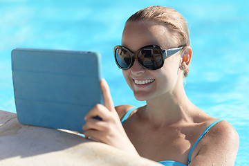 Image showing Young woman in a pool using tablet computer