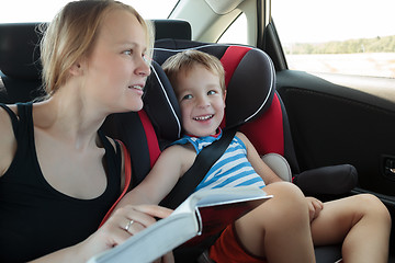 Image showing Mother reading a book to son in the car