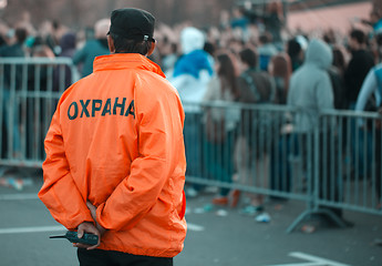 Image showing Back security guard in front of blurred crowd