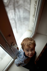 Image showing Smiling boy sitting on the windowsill.