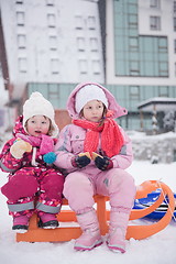 Image showing portrait of two little girls sitting together on sledges