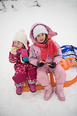 Image showing portrait of two little girls sitting together on sledges