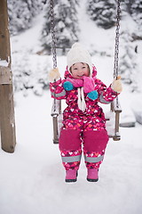 Image showing little girl at snowy winter day swing in park