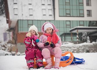 Image showing portrait of two little girls sitting together on sledges