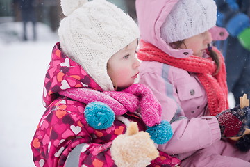 Image showing portrait of two little girls sitting together on sledges